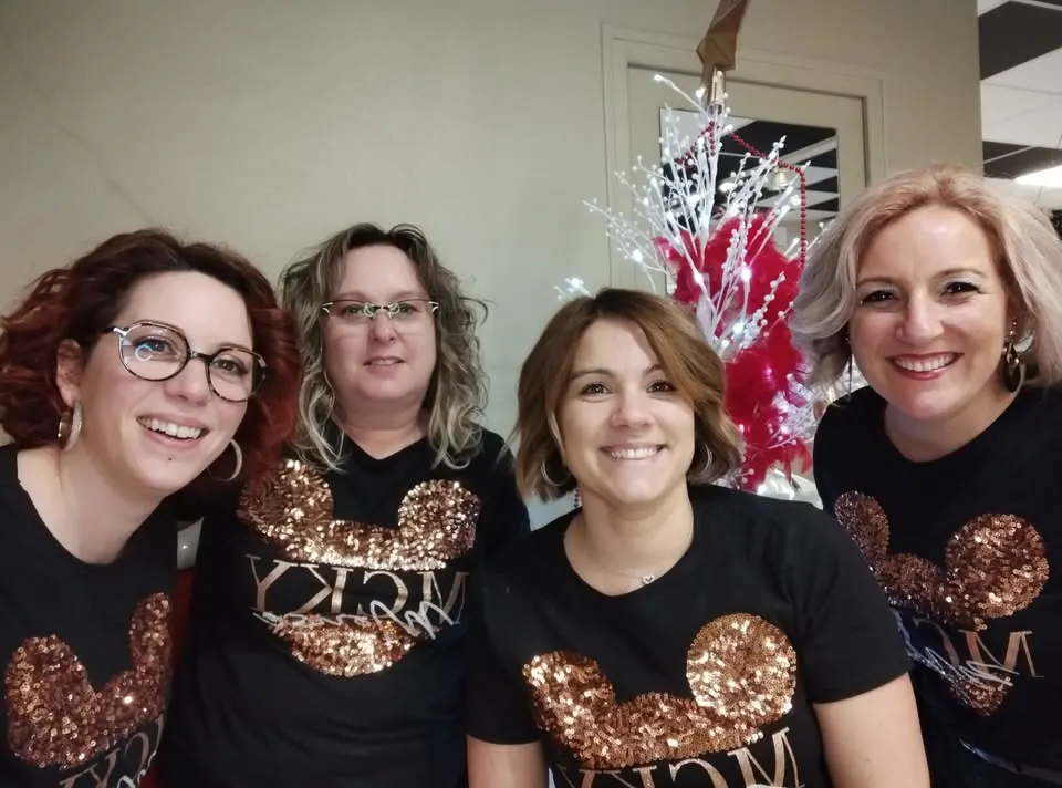 Les quatre coiffeuses du salon, en tee-shirt noir, devant un sapin de Noël